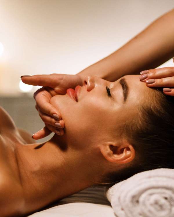 Woman enjoying anti aging facial massage in atmospheric spa, side view